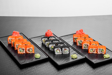 Maki Sushi set on dark pattern background. Sushi Set nigiri, rolls and sashimi served in black square plate. On dark pattern background.