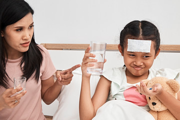 Mother feeding syrup medicine to little girl