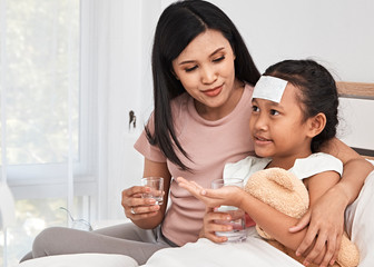 Mother feeding syrup medicine to little girl