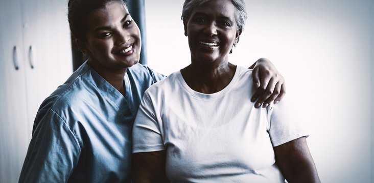 Portrait Of Young Nurse With Patient In Nursing Home