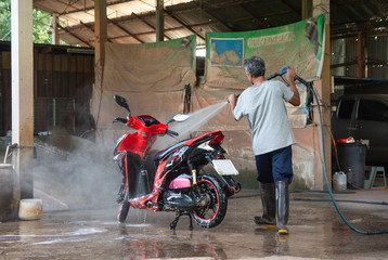 Old man wash your motorcycle with High Pressure Washer at car wash shop