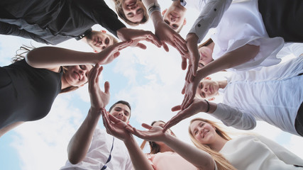 A group of high school students look through the shape of a circle created from their palms. The...