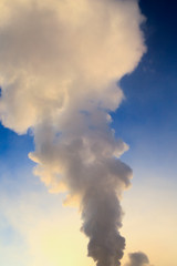 Smoke from factory pipes against blue sky. Concept of oil and gas processing plants, coal mining and minerals
