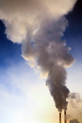 Fototapeta na wymiar Smoke from factory pipes against blue sky. Concept of oil and gas processing plants, coal mining and minerals