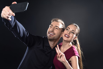 happy young couple taking selfie with smartphone isolated on black