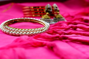 Indian ethnic jewelry bracelets and earrings on pink fabric