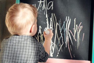 Black chalk Board scribbled little boy colored crayons. Learning the alphabet and preparing for...