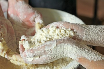 Hands of mother and daughter kneading dough together in the kitchen