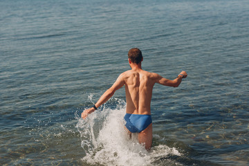 Fototapeta premium A young man swims in the sea against the backdrop of mountains
