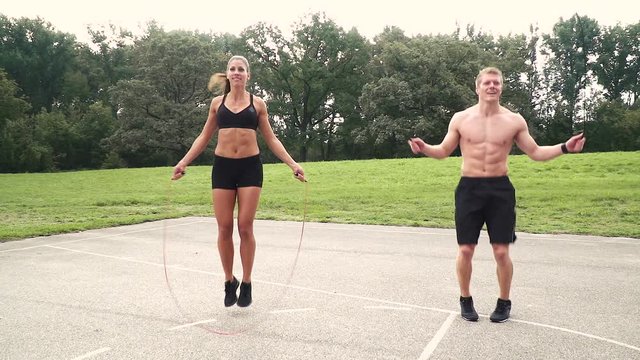 2 muscular athletes jump with the spring rope, outdoor in the morning