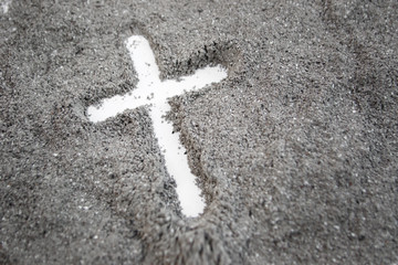 Christian cross or crucifix drawing in ash, dust or sand as symbol of religion, sacrifice,...