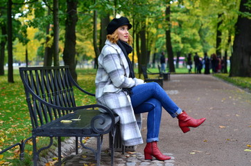 young woman sitting on a bench in autumn park