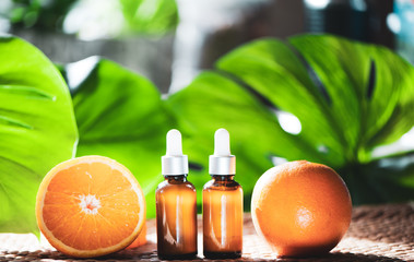 Bottles with orange oil, fresh  fruit whole and half on a natural tropical background.