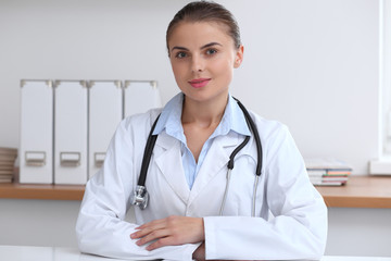 Doctor woman writing papers at the desk in hospital office. Medicine and over work concept