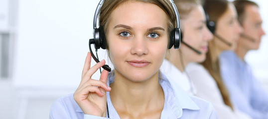 Call center operator in headset while consulting client. Telemarketing or phone sales