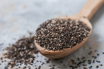 Wooden spoon with chia seeds on grey  background, sellective focus. Superfood