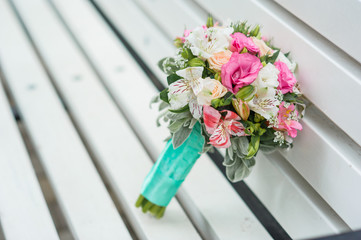 wedding bouquet lies on a wooden bench