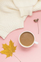 Cup of coffee and white sweater on pink background