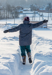 Running woman on snowy country path in winter sunny day