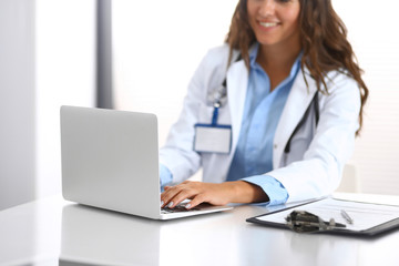 Unknown doctor woman typing on laptop computer while sitting at the desk in hospital office. close-up of hands. Physician at work. Medicine and health care concept