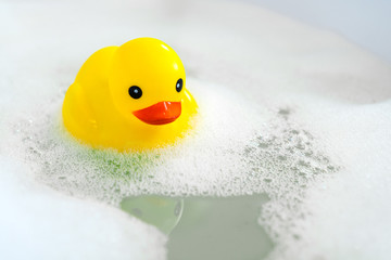 One yellow rubber duck with soap bubble bath, light  background with bubbles. Kids spa concept. Children`s bath time concept.