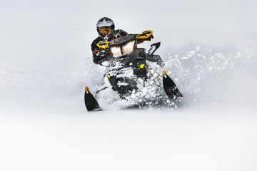 In deep snowdrift snowmobile rider make fast turn. Riding with fun in deep snow powder during...