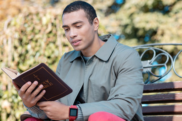 Fototapeta premium Concentrated religious man reading Bible in park
