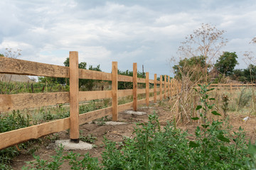 Ranch style fence. Rural wooden fence on green grass at farm ranch land in Shagany, Ukraina.