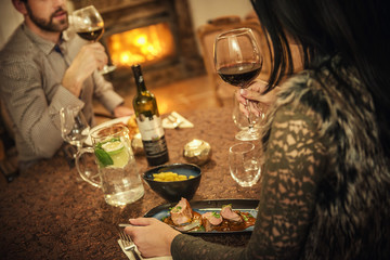 pretty couple drinking red wine and eating in restaurant, winter time, romantic dinner