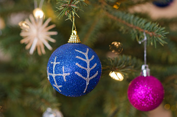 Two decorative balls on christmas tree branch.