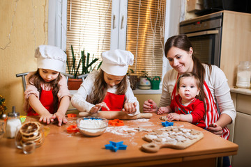 Merry Christmas and Happy Holidays. Family preparation holiday food. Mother and daughters cooking Christmas cookies.