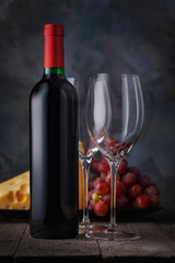 Bottle of red wine and two empty glasses close-up on a wooden table. Still life with alcohol