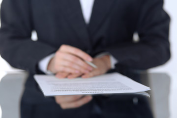 Close-up of female hands with pen over document,  business concept. Lawyer or business woman at work in office