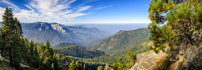 Landscape in Sequoia National Park in Sierra Nevada mountains on a sunny day; smoke from wildfires visible in the background, covering the Fresno area;