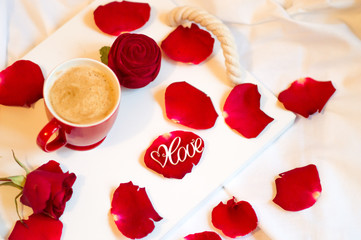 The morning of February 14, coffee in bed with a gift and flowers, rose petals on the bed for the woman he loves. Valentine's Day Surprise