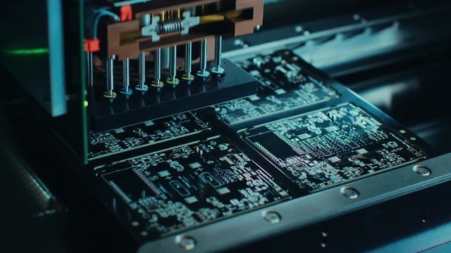 Factory Machinery at Work: Printed Circuit Board Being Assembled with Automated Robotic Arm, Surface Mounted Technology Connecting Microchips to the Motherboard. Macro Close-up Footage.