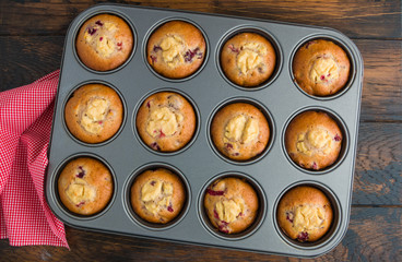 Cranberry muffins with ricotta in baking form on wooden table, top view