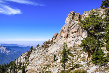 High altitude landscape in Sequoia National Park, Sierra Nevada mountains; blue sky and smoke from wildfires covering the valley visible in the background; California