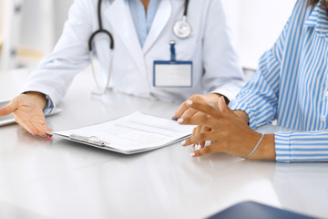 Doctor and patient talking and discussing health treatment while sitting at the desk, close-up. Medicine and health care concept