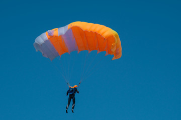 Skydiver is flying with parachute in blue sky