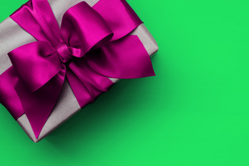 Gift box with pink ribbon on green background