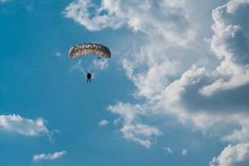 Skydiver with parachute on epic clouds and blue sky background. Copy space