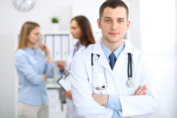 Friendly male doctor  on the background with patient  and physician
