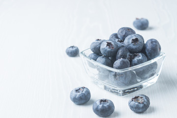 Fresh blueberries in a glass cup on a light background