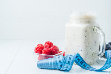 Raspberry smoothies on a light background, a centimeter for measuring the waist
