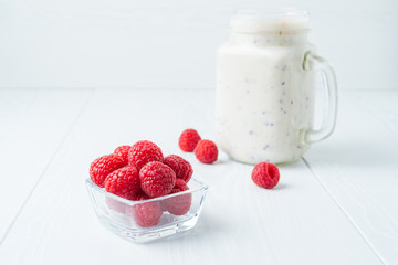 Red raspberries in a glass cup close up and a milkshake