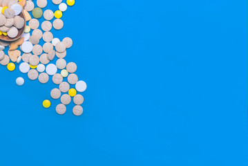 Top view of pharmaceutical medicine pills, capsules and tablets w/ wooden spoon on light blue background. Vitamin and supplement. Health behavior concept. Minimal style. Creative idea.