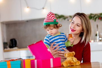 beautiful mother with son wrapping a gift boxes against the background of the scenery for Christmas in the kitchen