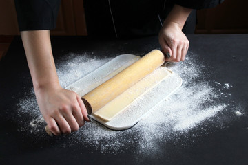Woman preparing buns from puff pastryat table in bakery. The cook preparing buns at table in...