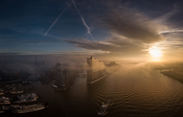 Elbphilharmonie mit Hafencity und Speicherstadt bei nebligem Sonnenaufgang